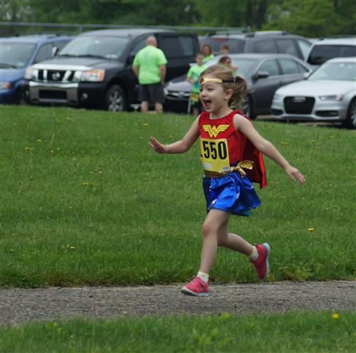 Excited girl running in her Wonder Woman costume 