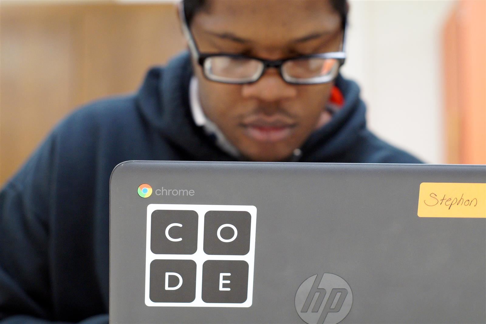 A student codes on his laptop during class.