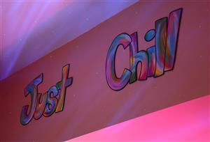  The words 'Just Chill' are painted on a wall lit by dots and waves of colored light.